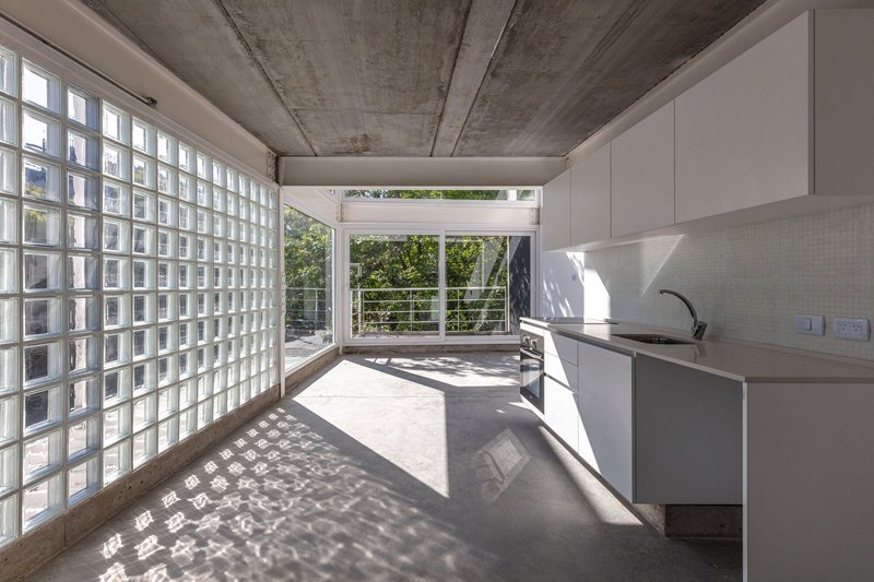 Interior kitchen with glass block wall casting dappled shadows on polished concrete floor