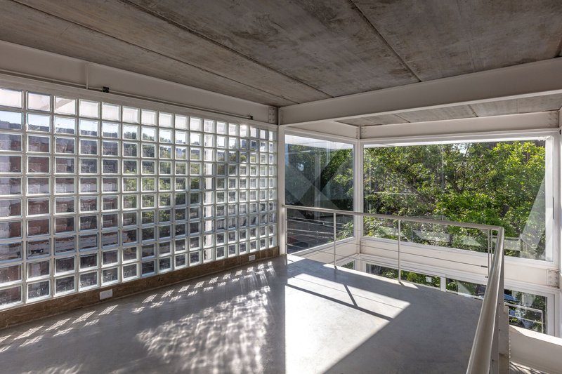 Corner terrace with glass block wall and cable railing overlooking trees in sunlight