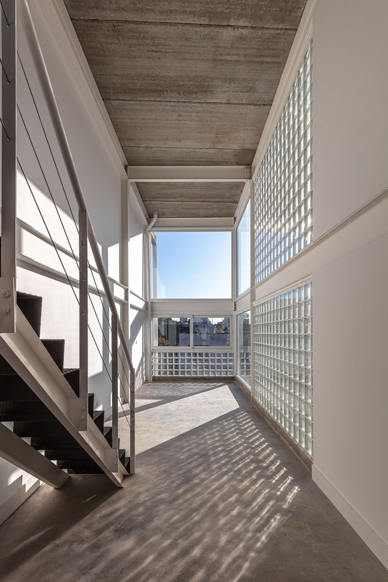 Interior corridor with board-formed concrete ceiling and glass block wall casting patterned shadows across the floor