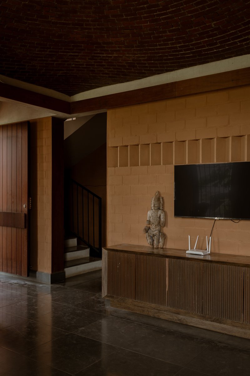 Interior living space with a curved brick vault ceiling above light sandstone walls and dark tile flooring
