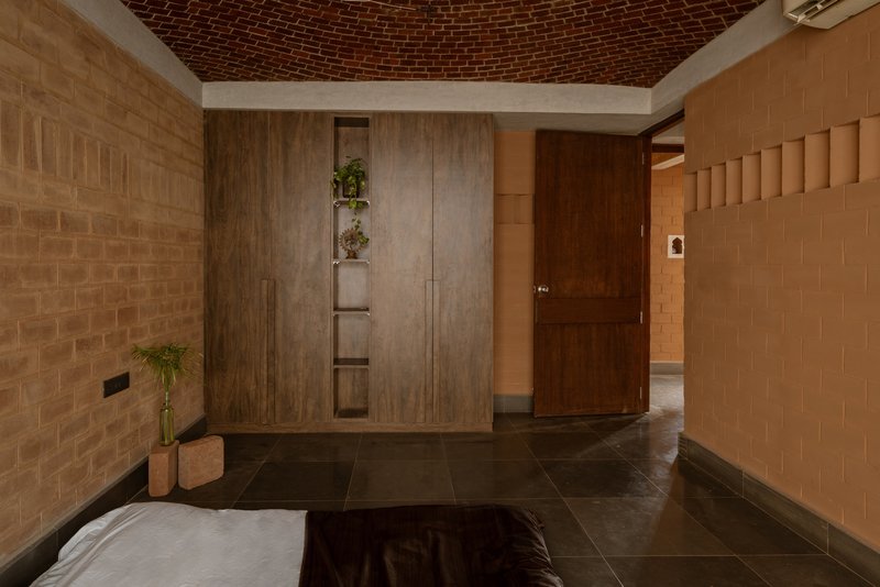 Entry foyer with timber door and wardrobe beneath a curved brick vault and corner planters