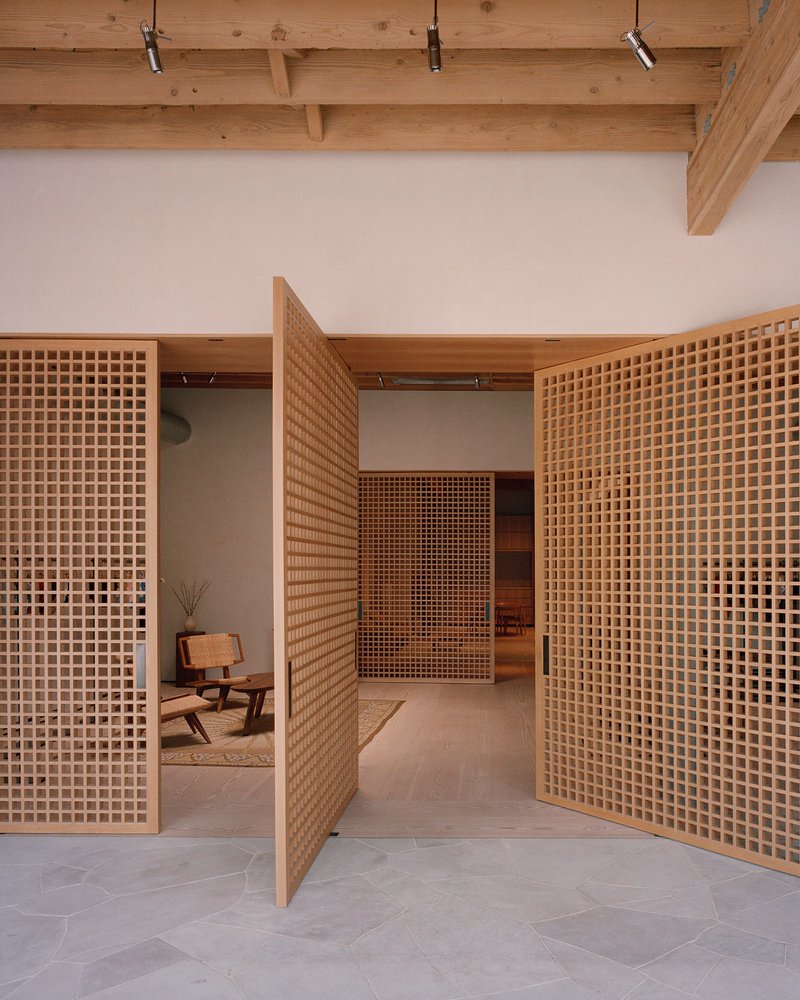 Timber lattice partition walls with square grid openings framing a seated area beneath a beam ceiling with track lighting