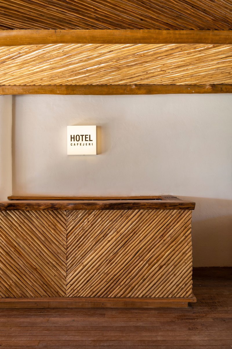 Reception desk with herringbone bamboo panels beneath diagonal slatted timber ceiling and wall-mounted signage