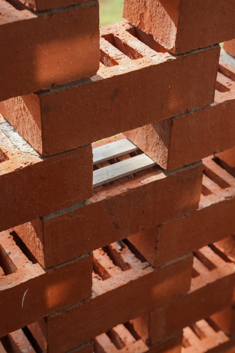 Close-up of the open-joint terracotta brickwork showing the staggered bond pattern in direct sunlight