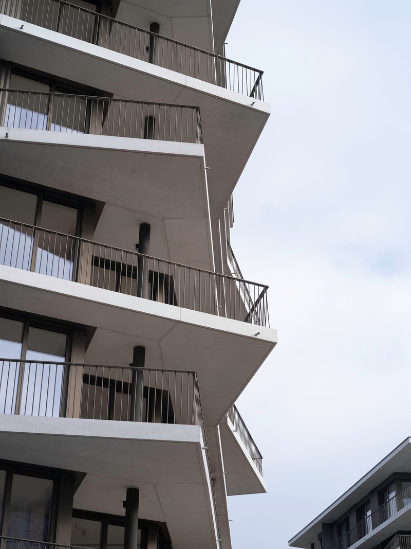 Stacked concrete balconies with protruding slabs and metal railings against an overcast sky