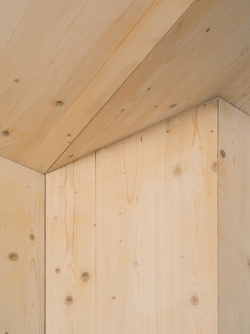 Detail of pale wood planks meeting at an internal corner with visible knots and grain