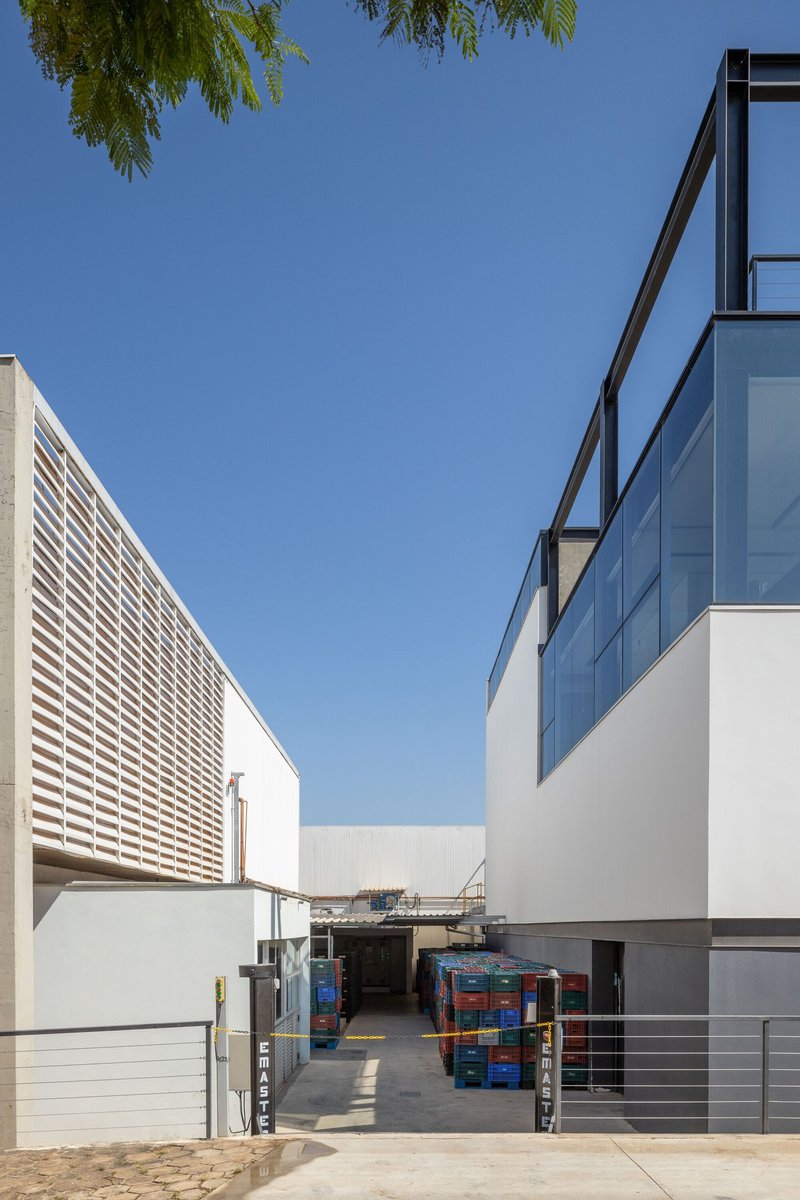 Courtyard entry passage between horizontal louvered screen and glazed volume under clear sky