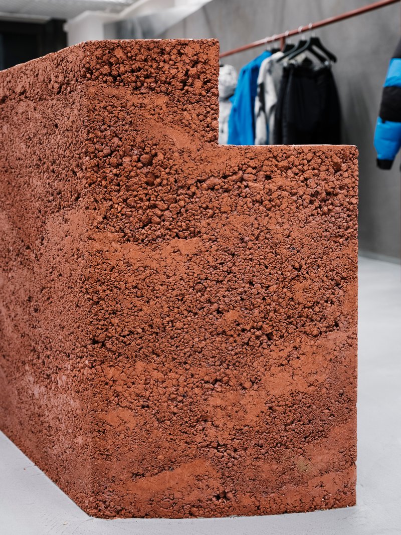 Curved reddish aggregate stair detail with clothing rack visible in the background space