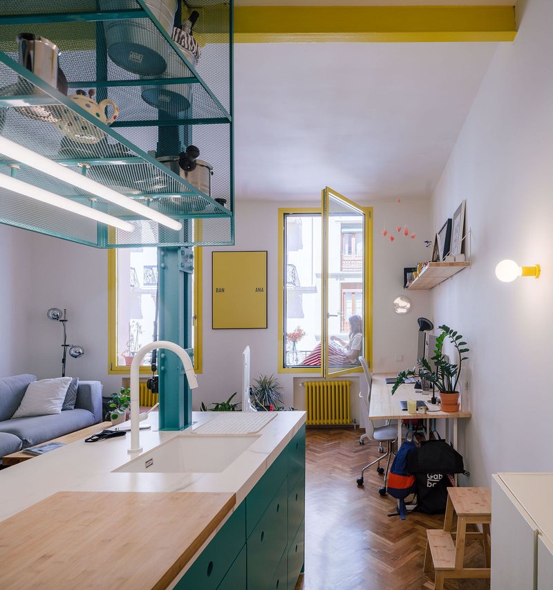 Kitchen with white countertop, teal arched faucet and perforated metal overhead storage shelving