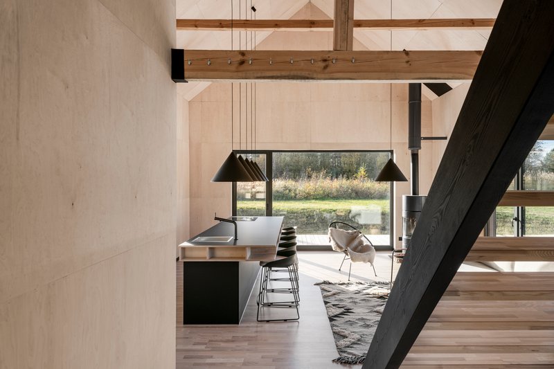Interior view showing exposed timber beams and black steel stair alongside kitchen island