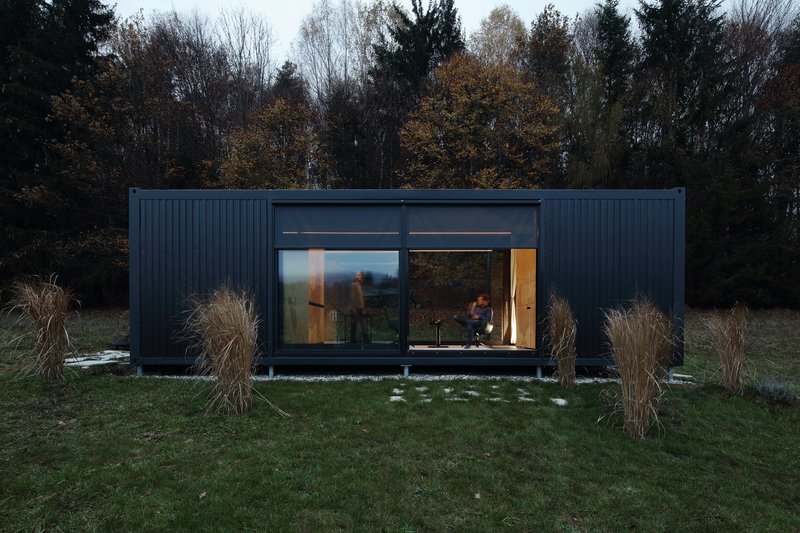 Front elevation showing full-height glazing with occupants inside at dusk