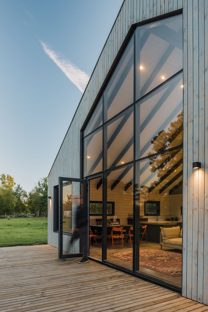 Open glass door revealing exposed timber rafters and interior living space from the timber deck