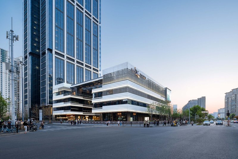 Corner view of the stacked horizontal volumes with alternating glass and louvered cladding at sunset