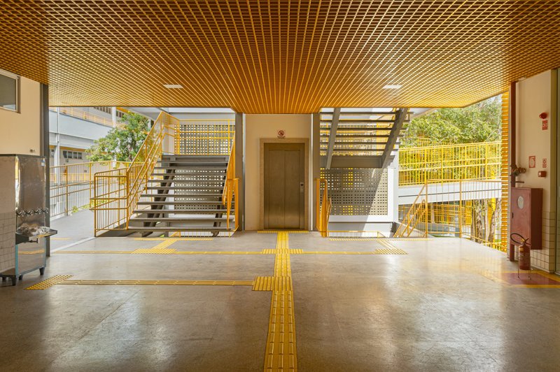 Lobby with yellow tactile pavement strips crossing polished concrete floor beneath slatted timber ceiling