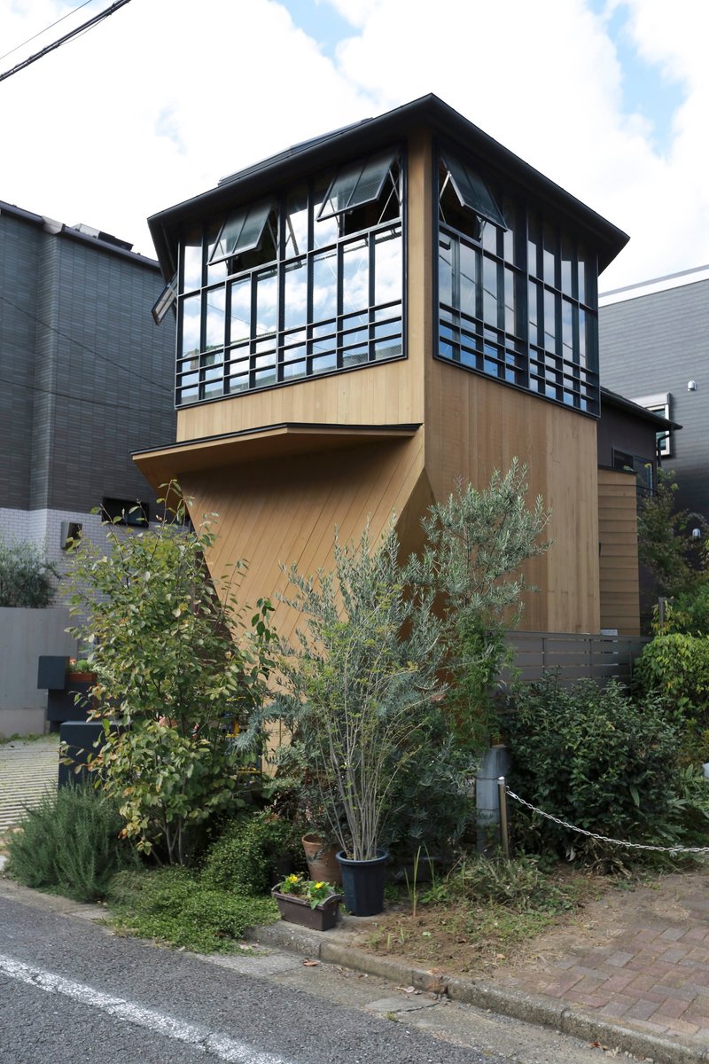 Garden approach showing the projecting upper floor clad in timber above potted plants