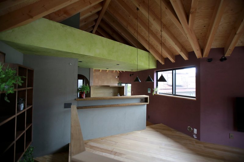 Open plan space with exposed timber rafters connecting kitchen and living area under daylight