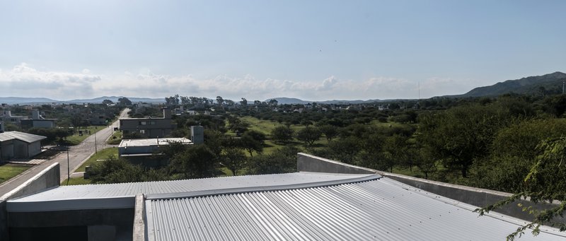 Corrugated metal roof planes extending over the suburban landscape with mountains in distance