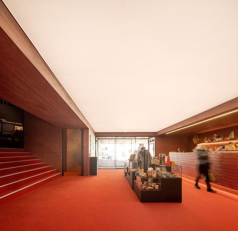 Museum shop interior with red resin floor, wood-clad walls and a visitor in motion