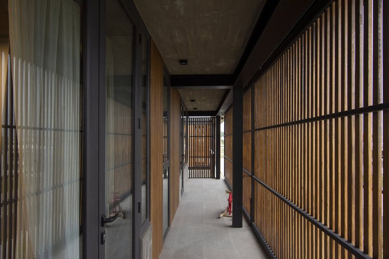 Corridor with concrete ceiling beams and vertical timber screens on one side with glazing on the other