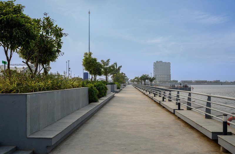 Waterfront promenade with concrete planters and metal railings under clear daytime sky