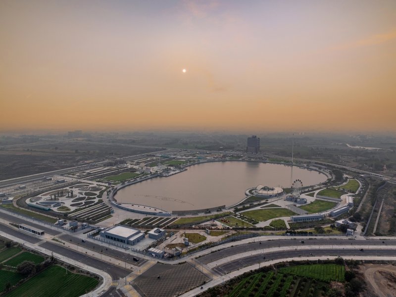 Aerial perspective of the circular lake surrounded by curved parkland and roadways at sunset