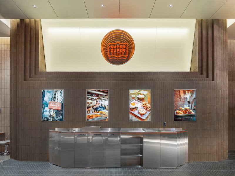 Service counter with stainless steel base and backlit wall displaying four framed food photographs