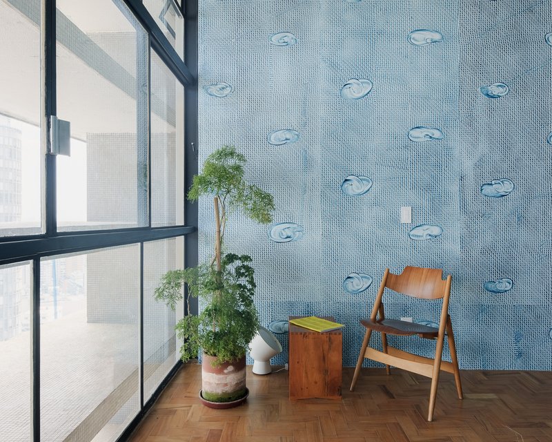 Blue mosaic tile wall with applied ceramic fish motifs beside a steel-framed window