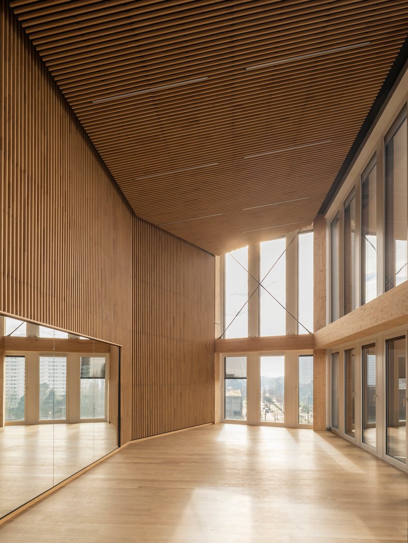 Double-height space with slatted timber ceiling and floor-to-ceiling windows overlooking the cityscape