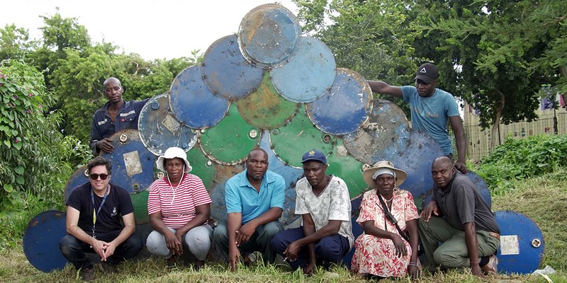 Group portrait in front of a weathered painted metal panel with circular and arched motifs