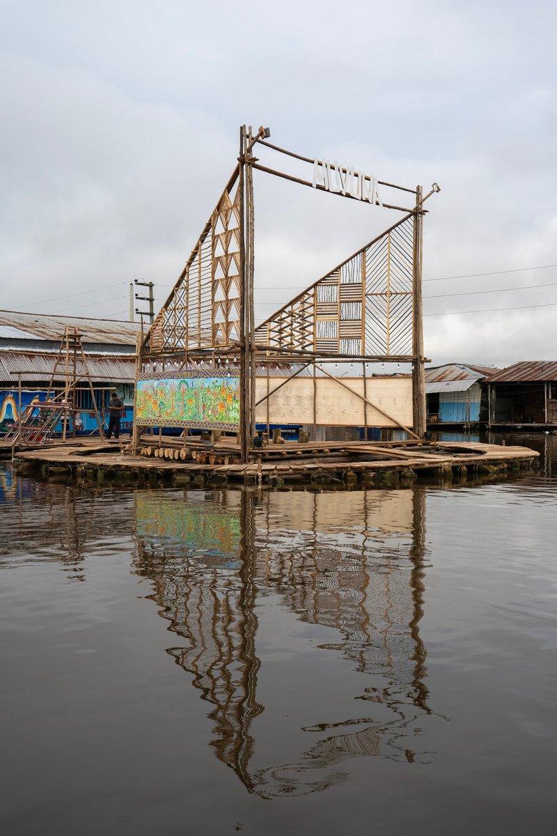 Floating bamboo and timber stage platform with geometric panels reflected in still water