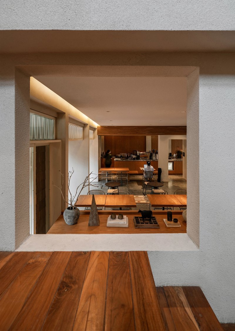 Deep window opening framing the dining area with timber flooring and overhead concealed lighting