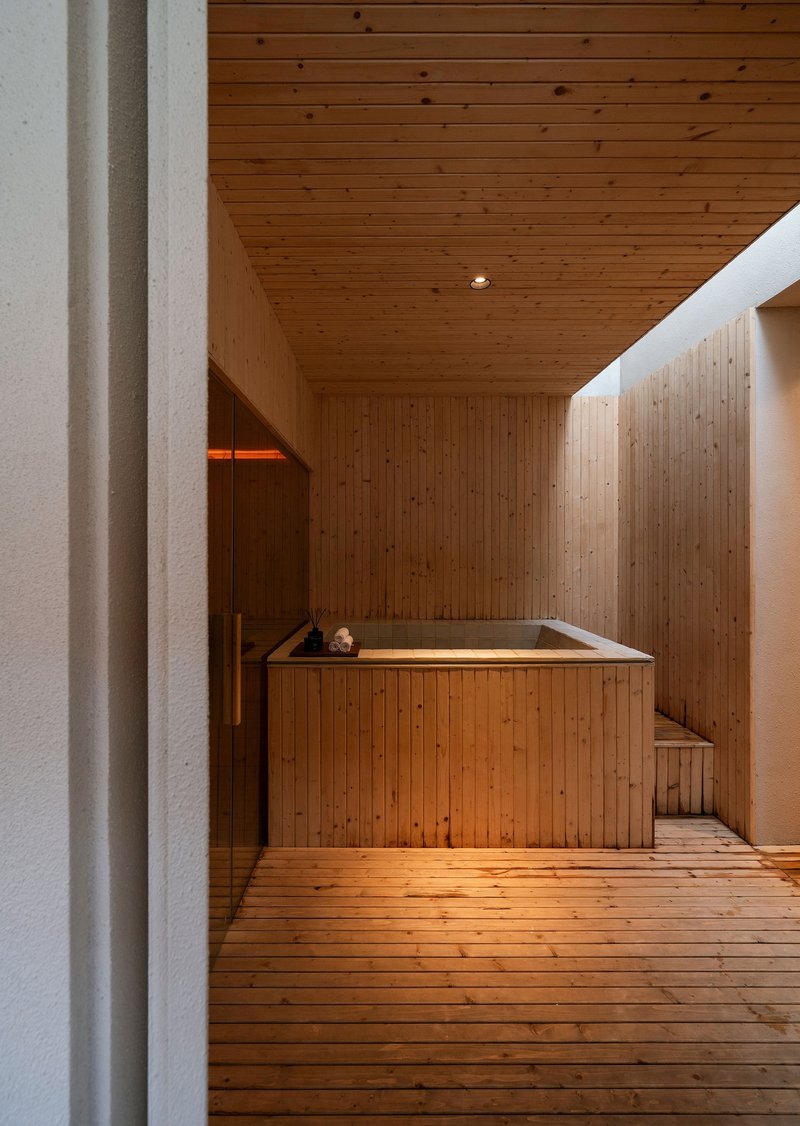 Cedar-lined bathing room with built-in timber soaking tub and plank floor under a wood ceiling