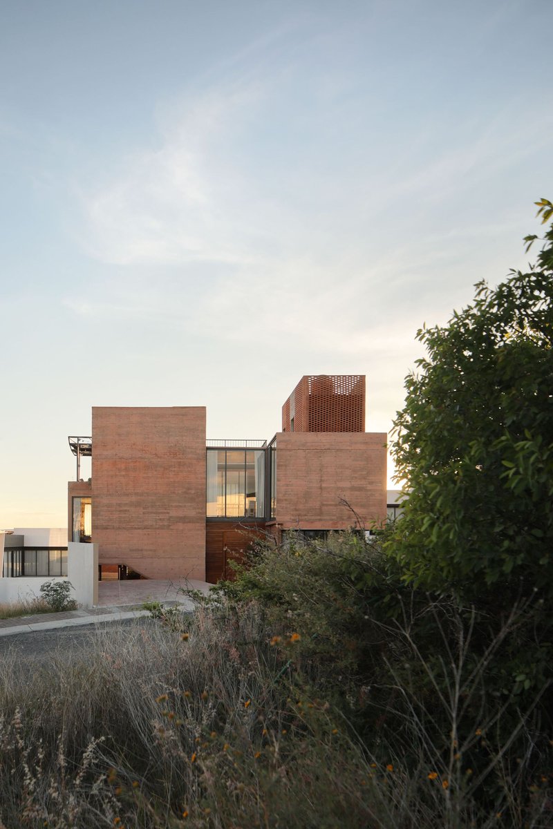 Red brick facade with perforated brick tower rising above planted native grasses at dusk