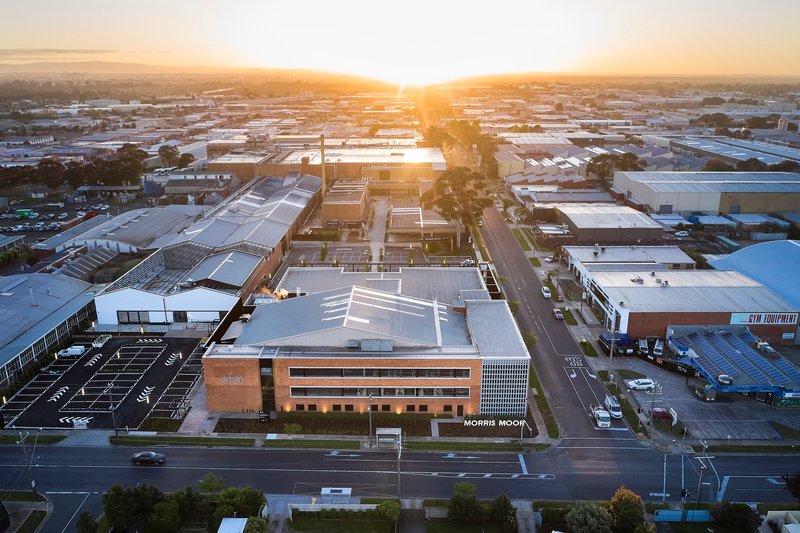 Aerial view of the timber and perforated metal facade among warehouses at sunset