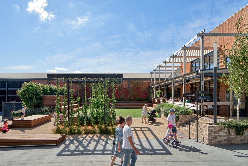 Elevated view of the courtyard with planted trellis structure and families moving through sunlit pathways
