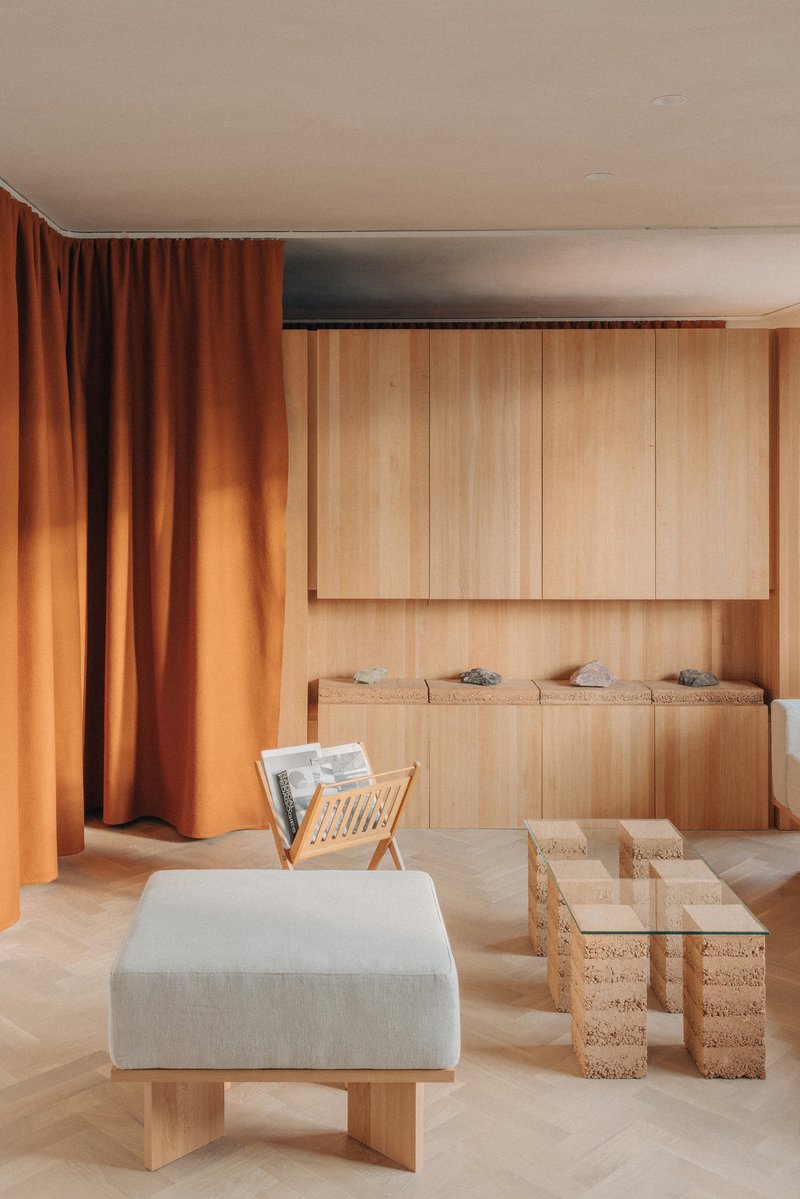Interior with vertical timber paneling, built-in bench seating, and cork block tables beneath a recessed ceiling