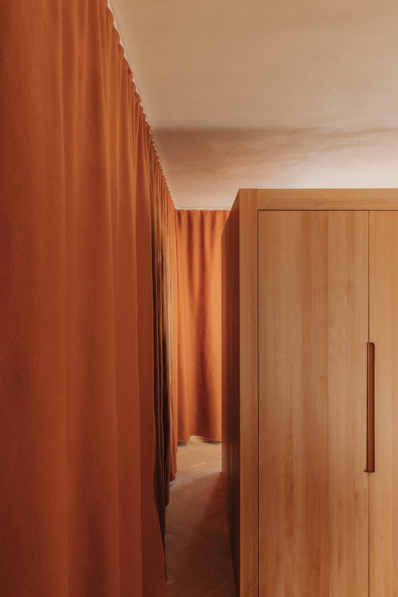 Narrow passage between terracotta fabric and timber wardrobe with vertical pull handle