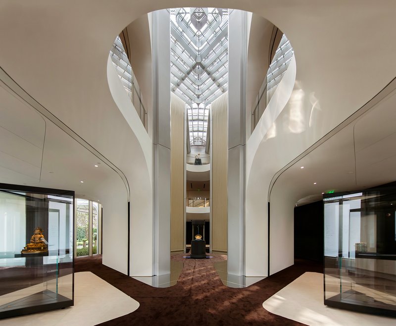 Multi-story atrium with fluted white columns and diamond-patterned skylight above a central display case