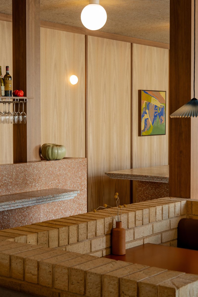 Split-level seating area with terrazzo counter and blonde timber steps lit by spherical pendant fixtures