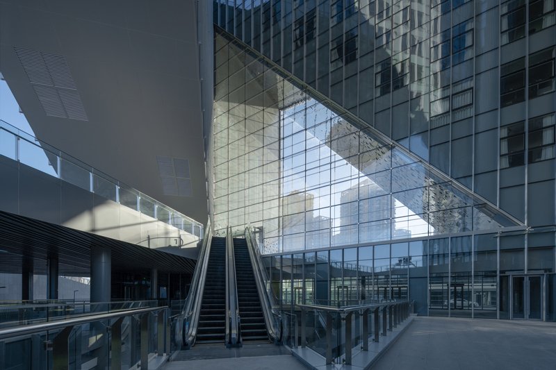 Covered atrium courtyard with twin escalators rising beneath the angled glass overhang