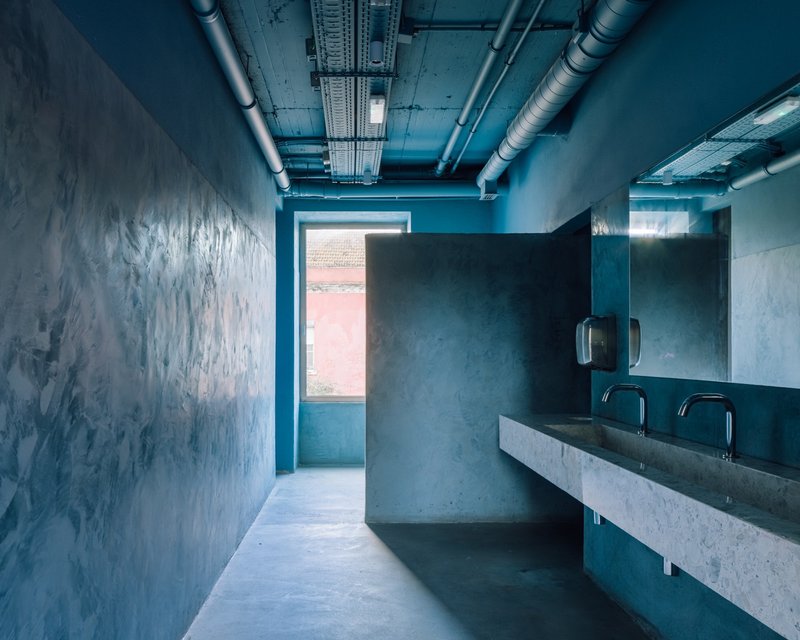 Washroom with blue polished plaster walls, concrete counter, and exposed ductwork at ceiling
