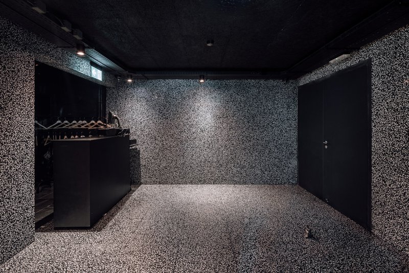 Black-walled room with terrazzo flooring and walls extending to ceiling under artificial light