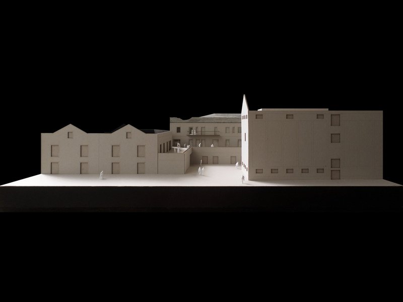 Sectional model displaying gabled roof volumes alongside flat-roofed blocks with a tower element between them