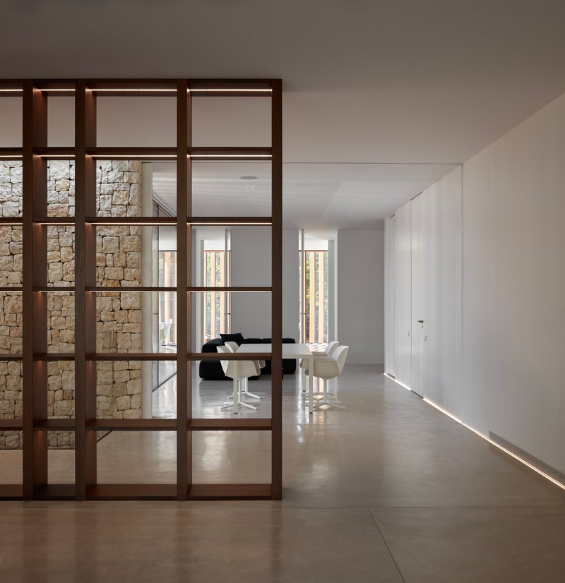 Dark timber framed glass partition dividing the corridor from the dining room with concealed floor lighting