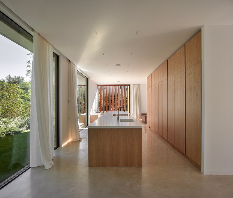 Kitchen with oak island and full-height cabinetry opening to a vertical timber screen beyond