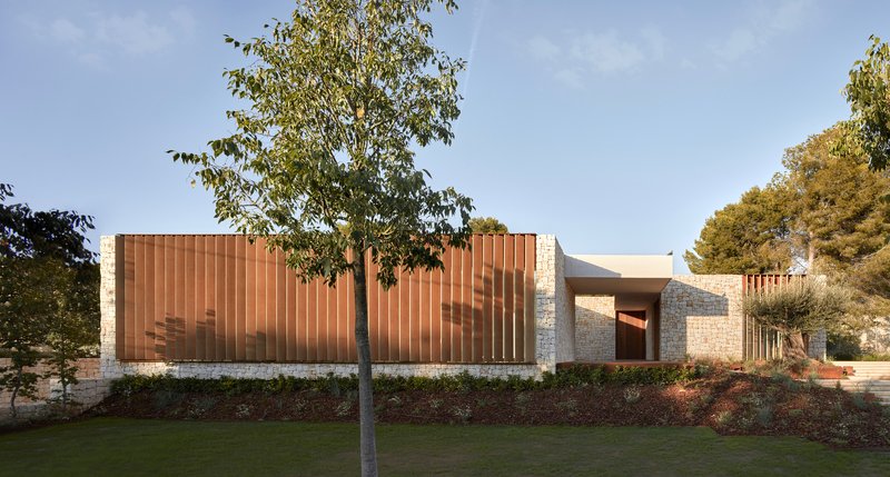 Street view showing vertical timber screen and stone plinth base with trees emerging from planted beds