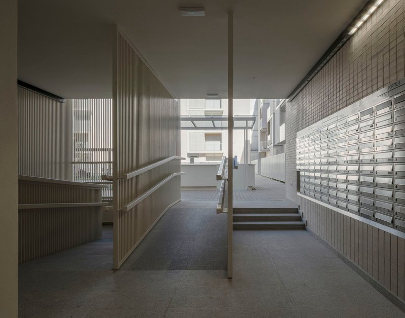 Ground floor lobby with metal mailboxes, ribbed wall panels and steps leading to glazed courtyard