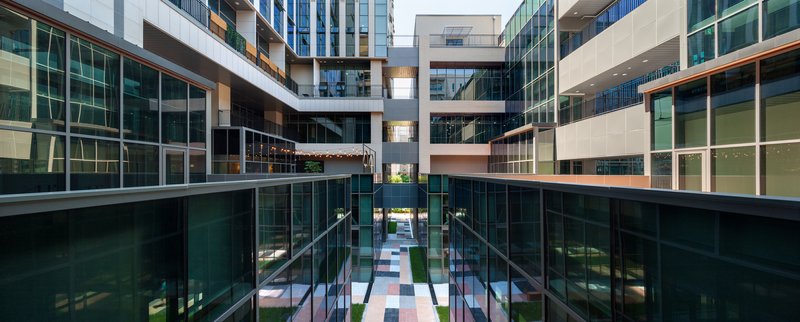 Glazed interior courtyard with bridges spanning between buildings at dusk with illuminated upper levels
