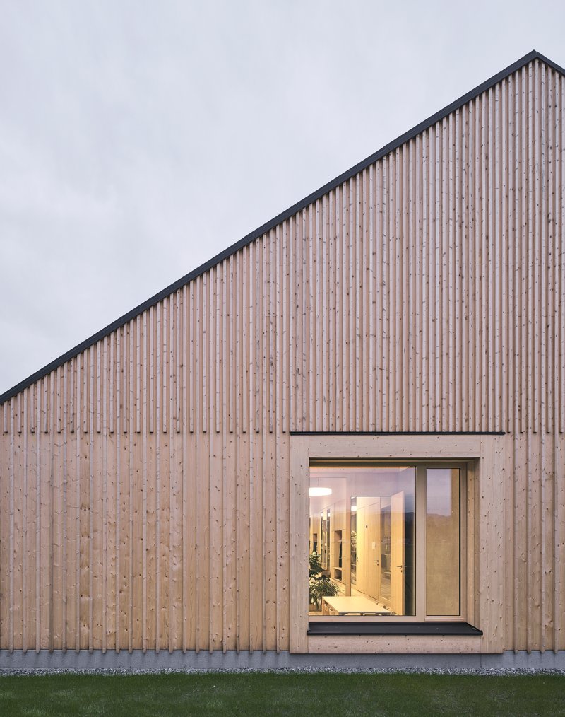 Close view of the vertical wood slat cladding and concrete-framed glazed opening