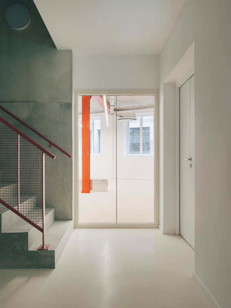 White floor hallway with concrete stair visible through doorway and circular ceiling light above